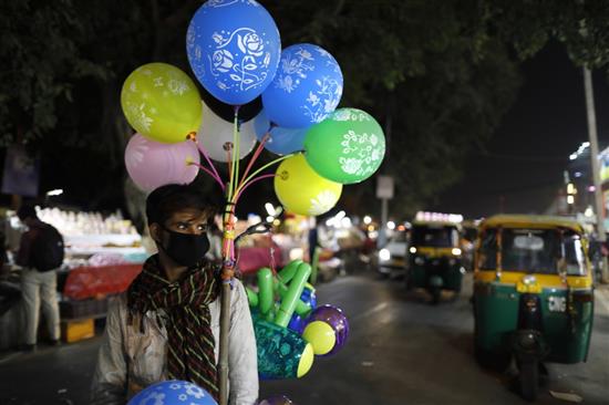 在印度新德里，一名售卖气球的小贩佩戴口罩工作。新华社 图
